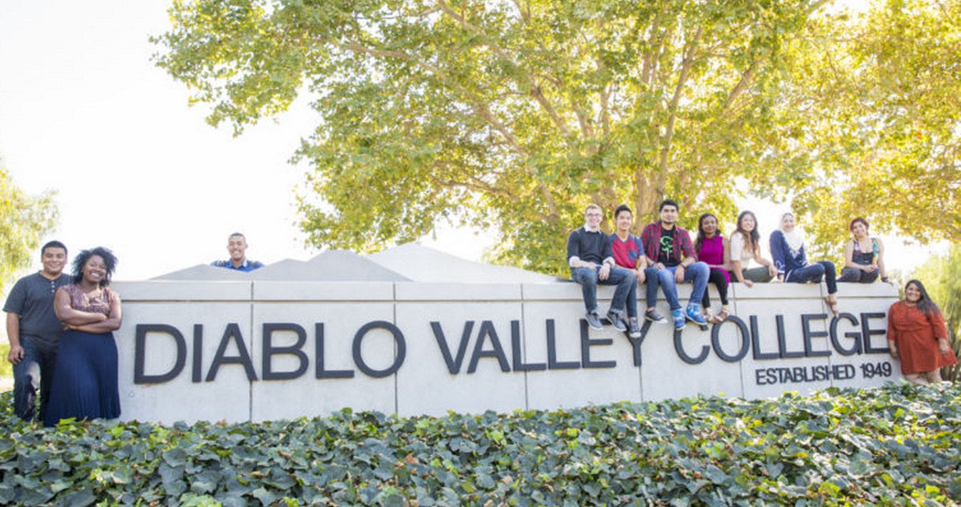 Group of Diablo Valley College students grouped around the campus sign