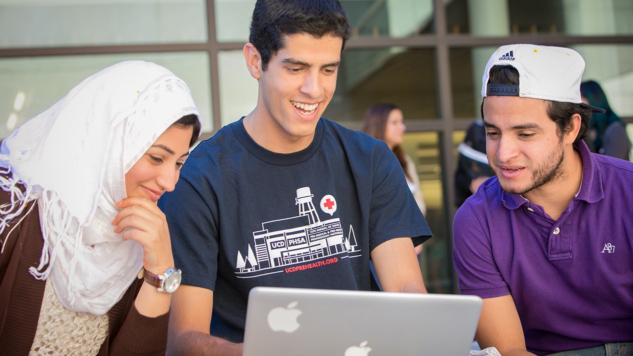 Three students looking at a laptop