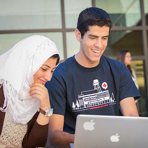 Three students looking at a laptop