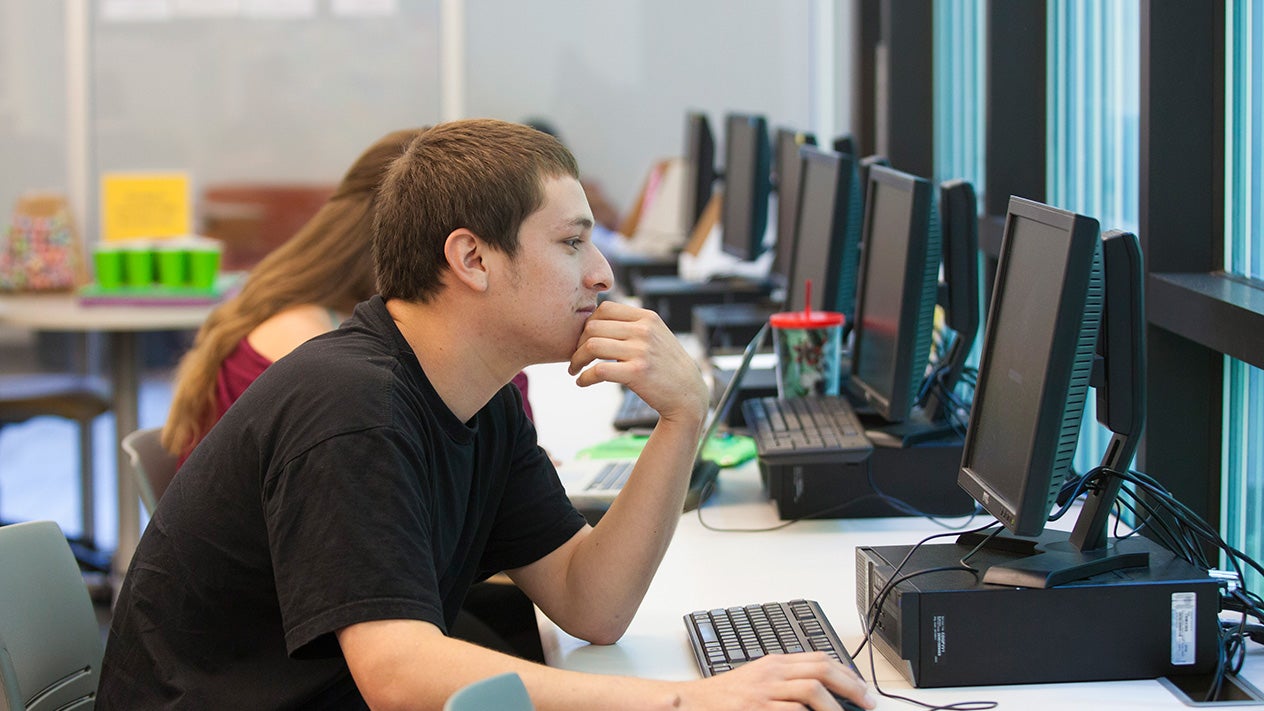 A DVC student at a workstation in a computer lab.