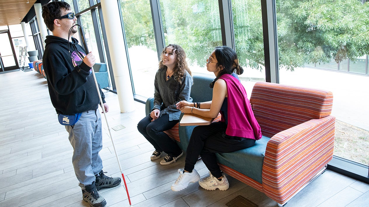 A blind DVC student talks with other students.