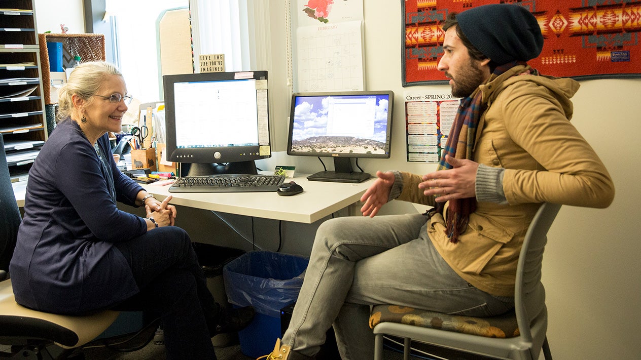 A student and counselor talking over a large desk.