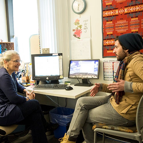 A student and counselor talking across a large desk.