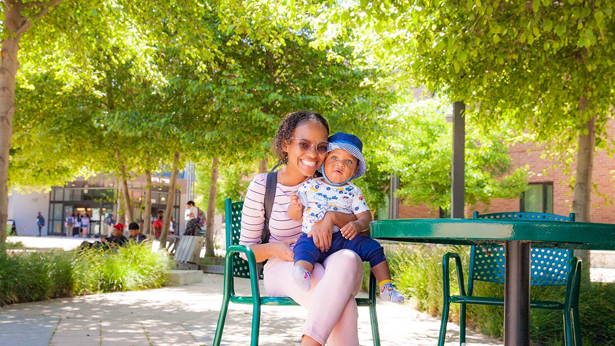 A student parent smiling with their young child.