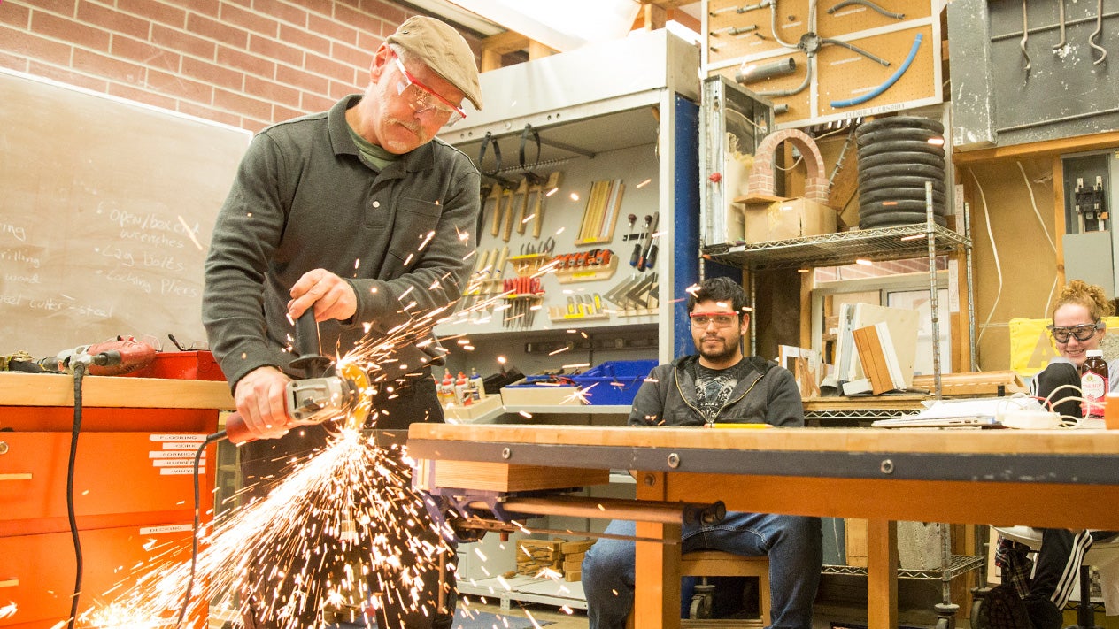 Construction teacher demonstrating tool to student