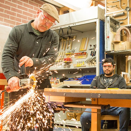 Construction teacher demonstrating tool to student