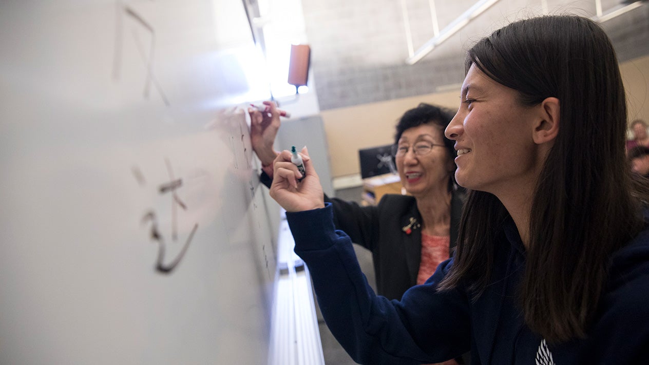 Teacher and student writing language on a whiteboard