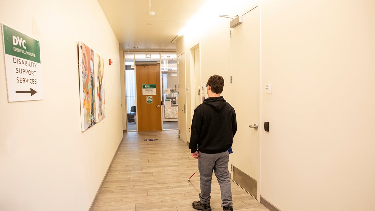 Visually impaired DVC student walking down hallway using a cane