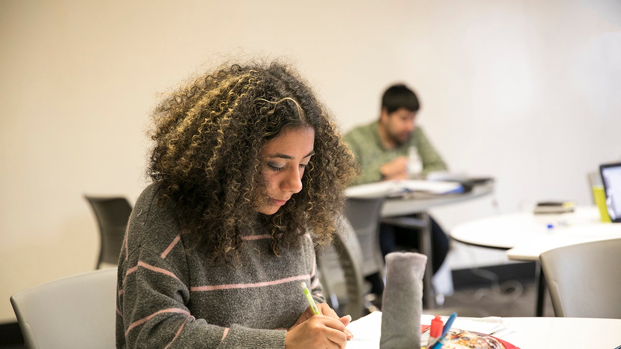 DVC student sitting at a desk and writing in a notebook