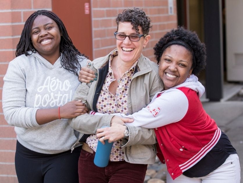 Three women smiling and hugging