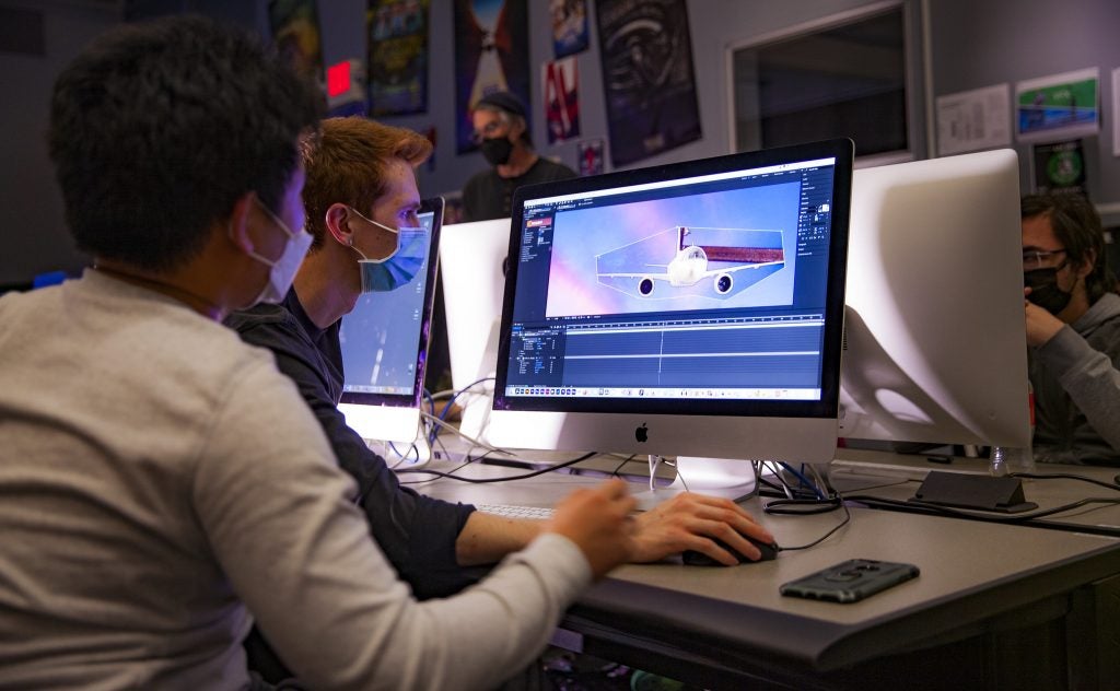 FTVE students working on their computers, with artwork on their monitor