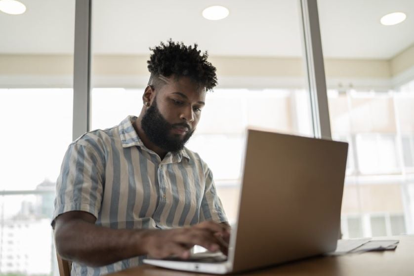 Student working on laptop while going to college remotely from home