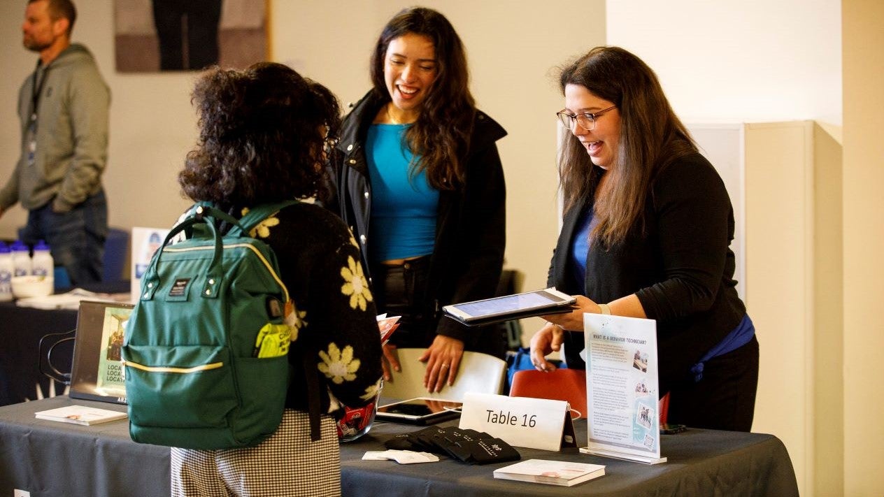 Employers greeting a DVC student at their booth at the DVC Spring Career Fair