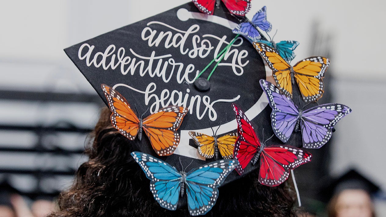 A DVC graduate with cap decorated with colorful butterflies.