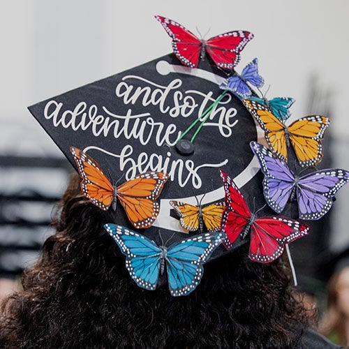 A DVC graduate with cap decorated with colorful butterflies.