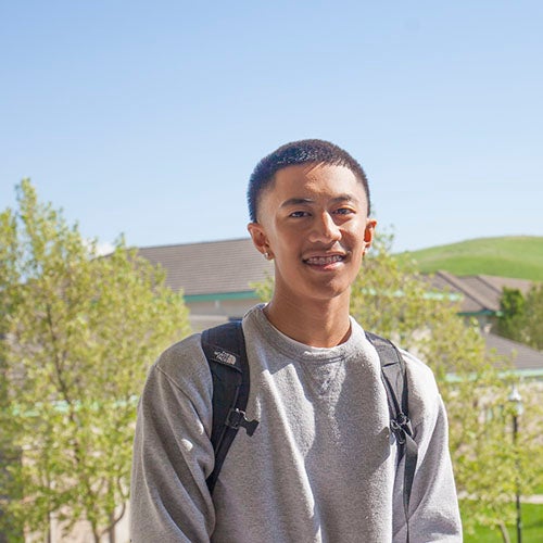 Student standing with green hills in background